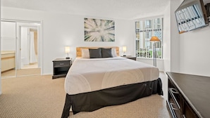 A modern hotel room with a large bed, a flat-screen TV mounted on the wall, and a large window offering a view of the outdoors. - Ski-in/Ski-out | Pool & Hot Tub | Sleeps 5! (Whistler)