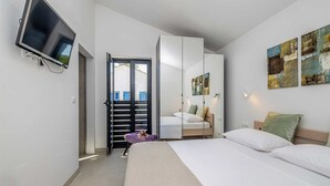 Moderni hotellihuone, jossa on sänky, televisio, vaatekaappi ja parveke, jolta on näkymä.