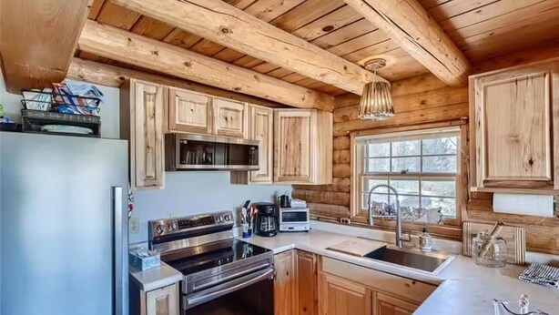 Een moderne keuken met houten kastjes, roestvrijstalen apparatuur en een groot raam.