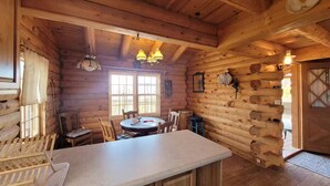Een gezellig chaletinterieur met houten inrichting, een eettafel, stoelen en een barhoek.