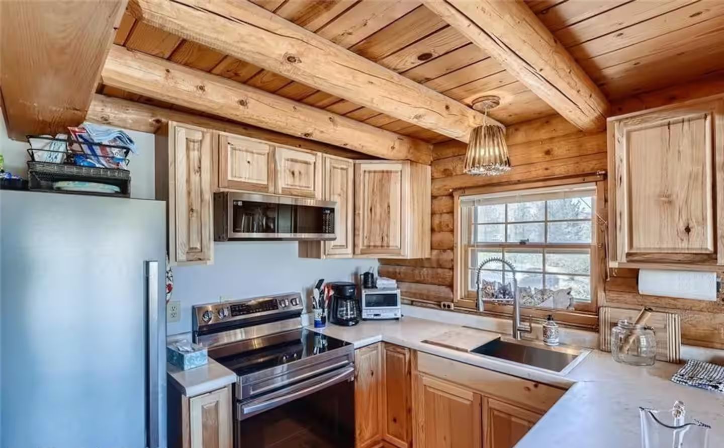 Una cocina moderna con armarios de madera, electrodomésticos de acero inoxidable y un amplio ventanal.