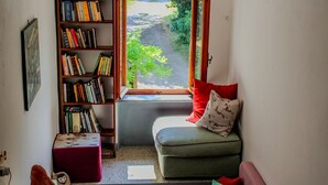 A cozy reading nook with a bookshelf, a cushioned bench, and a small table with a red pillow.