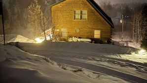 A wooden cabin with a sloped roof, a front porch, and a window with curtains. - Peaceful 2-bedroom apartment - dogs welcome (Granby)