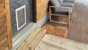 A log cabin with a dark front door, large windows, and a covered porch with two cushioned benches. - Peaceful 2-bedroom apartment - dogs welcome (Granby)