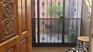 Une porte en bois ornée de sculptures complexes, un tapis à motifs et un banc recouvert d’un tissu à motifs.