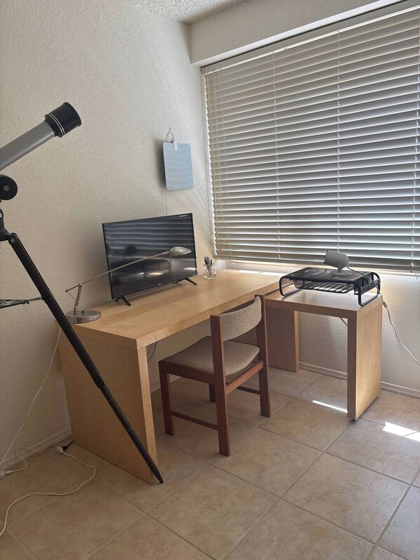 Un espace de travail comprenant un bureau en bois, une chaise, un ordinateur et une lampe.