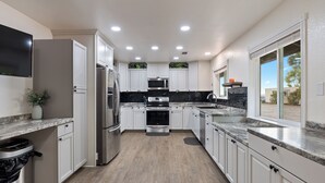 Una cocina moderna con armarios blancos, electrodomésticos de acero inoxidable y salpicadero negro.