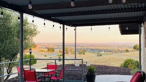 A covered patio with outdoor seating, a flag, and a view of the countryside.