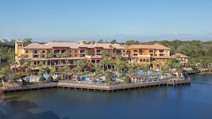 A multi-story hotel with a pool area, located near a body of water. - Stay in Exciting Orlando - 2BD Suite! (Lake Buena Vista)