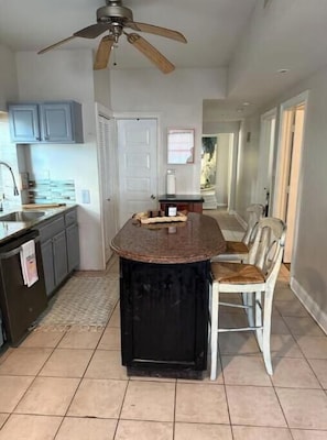 A kitchen with a central island, a ceiling fan, and a dining area with a chair.