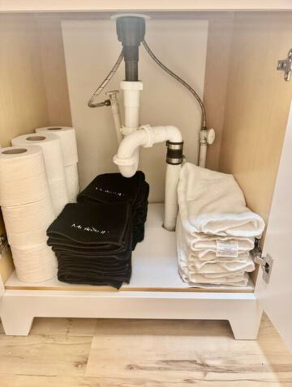 Un baño con un dispensador de papel higiénico, un perchero para toallas y una pila de toallas dobladas.