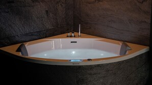 A modern bathroom with a freestanding bathtub, stone walls, and wall-mounted lighting. - Jungle Suite with Spa Bath – Exotic Getaway in Le Havre (Le Havre)