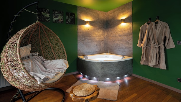 A room with a hanging chair, a bathtub, and a robe rack. - Jungle Suite with Spa Bath – Exotic Getaway in Le Havre (Le Havre)