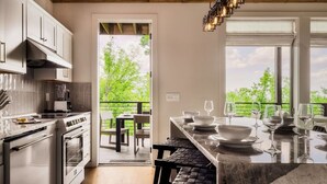 A modern kitchen with white cabinets, a marble countertop, and a view of the outdoors. - POOL/Sauna/Hot Tub/VIEWS! - Half Moon Haven (Gatlinburg)