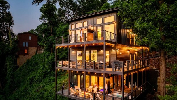 A multi-level wooden cabin with a balcony, surrounded by lush greenery. - POOL/Sauna/Hot Tub/VIEWS! - Half Moon Haven (Gatlinburg)