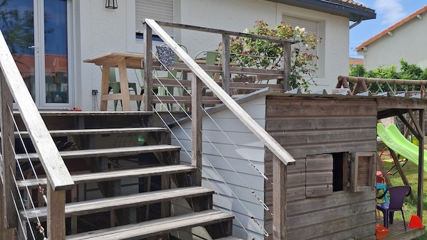 Una escalera de madera que conduce a un edificio blanco con techo de tejas.