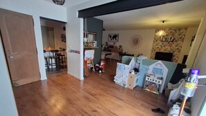 Amplia sala de estar con piso de madera, una casita de juegos y un comedor con sillas y una mesa.