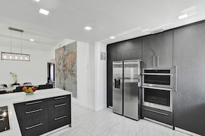Una cocina moderna con una isla grande, electrodomésticos de acero inoxidable y un mapa mundial en la pared.
