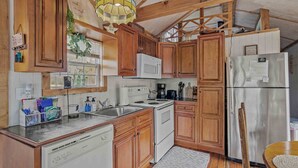 Eine Küche mit Holzausstattung, einem weißen Kühlschrank, einer Mikrowelle und einer Kaffeemaschine.