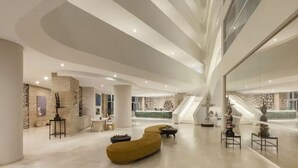 A spacious lobby with a modern design, featuring a central seating area, a staircase, and a reception desk. - New luxury resort on Medano Beach, (Cabo San Lucas)