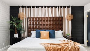 A modern bedroom with a geometric-patterned headboard, a large bed with multiple pillows, and a potted plant. - Ultimate Scottsdale Getaway | Heated Pool & Fire Pit | Game Room (Scottsdale)