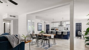 A modern kitchen with a central island, bar stools, and a dining area with a table and chairs. - Ultimate Scottsdale Getaway | Heated Pool & Fire Pit | Game Room (Scottsdale)