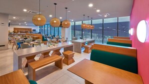A modern dining area with wooden tables and benches, large windows, and hanging spherical light fixtures. - Chic Modern Retreat w/ Rooftop Pool Conveniently Located in the City Center (Mérida)