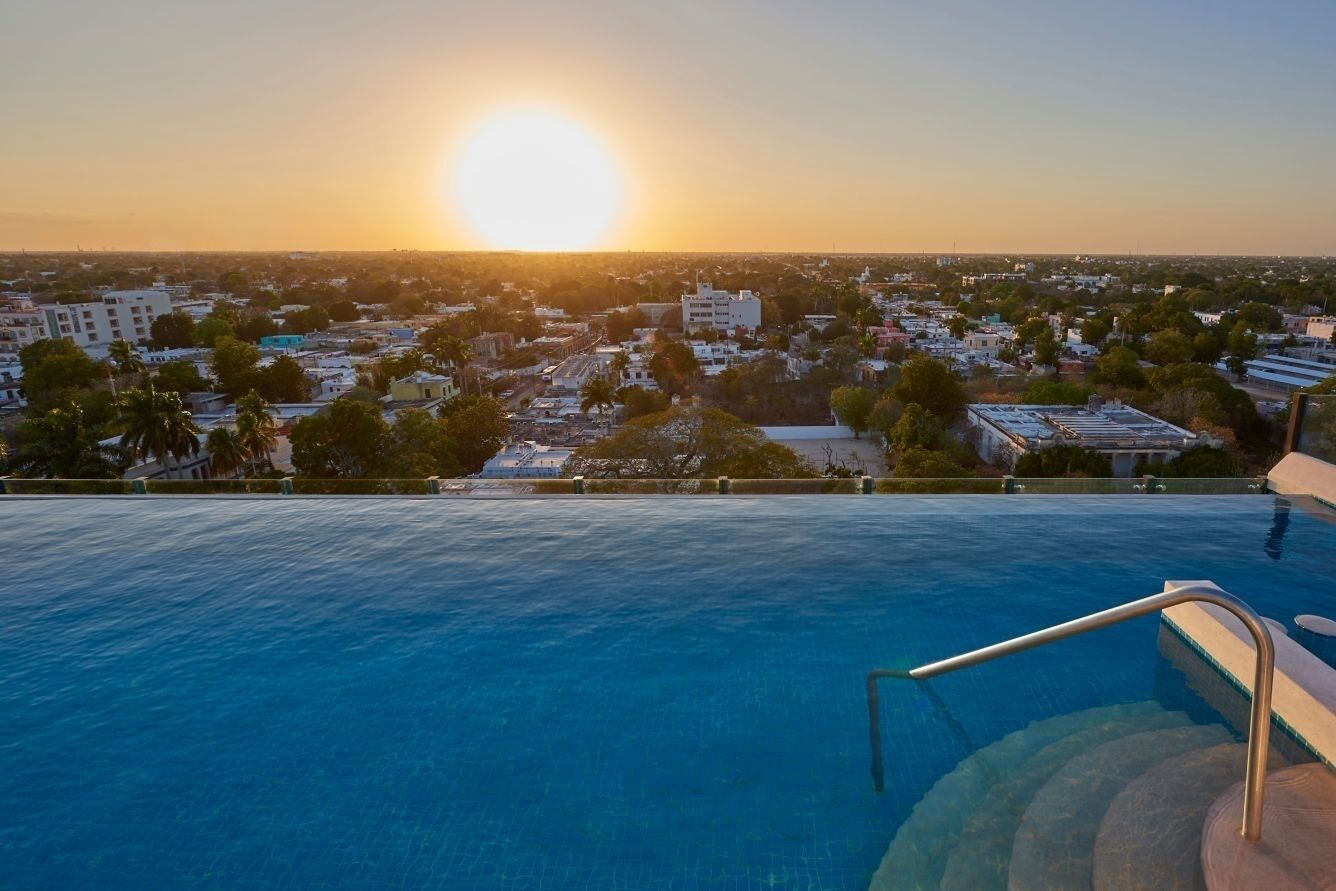 A swimming pool with a view of a cityscape at sunset.
