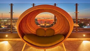 A wicker chair with a circular window overlooking a cityscape at dusk. - Walk to Everything from Your Mérida Rooms - 4 Units (Mérida)