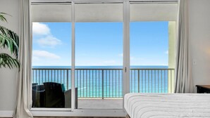 A bedroom with a large sliding glass door leading to a balcony with a view of the ocean. - Majestic Beach Towers 1-1909 (Panama City Beach)