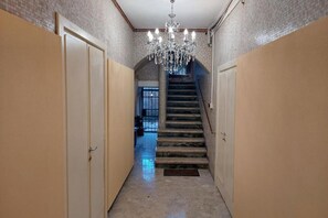 A hallway with a chandelier, a staircase, and doors on either side. - Donini Residence in Venice Suite 1  (venezia)