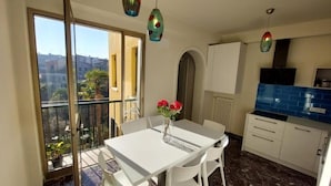 Uma cozinha moderna com armários brancos, um mosaico azul atrás do fogão e uma área de refeições com uma mesa e cadeiras brancas.