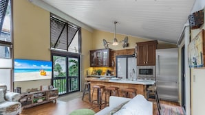 A spacious living area with a large window, a kitchen with modern appliances, and a cozy seating area. - Little Sandy Cove Paradise (Siesta Key)