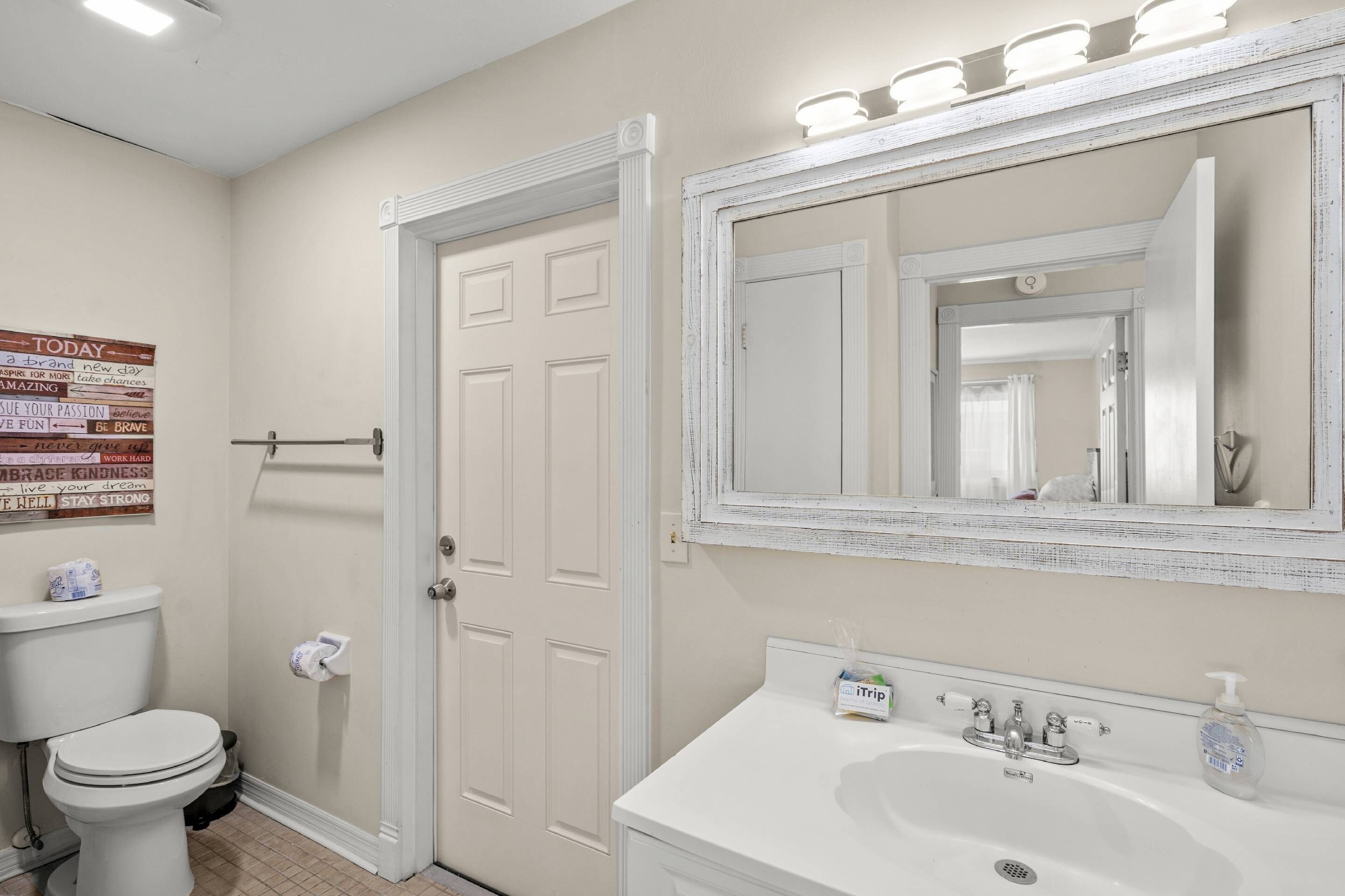 A bathroom with a toilet, sink, and mirror.