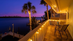 A balcony with a view of the water, palm trees, and a chair. - Coastal Breeze Siesta - Pelican (Siesta Key)