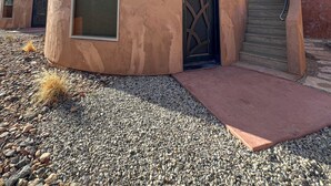 A circular building with a large window and a door, surrounded by gravel and sparse vegetation. - Zion White Bison (Virgin)