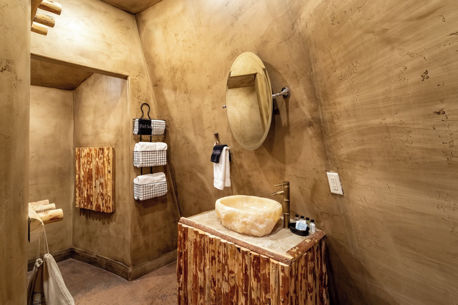 Une salle de bain avec un meuble-lavabo en bois, un grand miroir et des serviettes suspendues à des crochets.