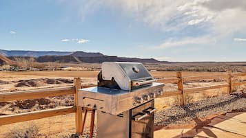 A barbecue grill with a wooden fence and a desert landscape in the background.