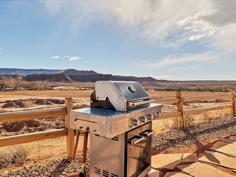 A barbecue grill with a wooden fence and a desert landscape in the background.