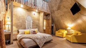 A cozy bedroom with a large bed, a dreamcatcher, and two yellow armchairs. - Zion White Bison (Virgin)