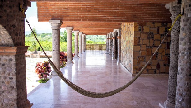 A covered corridor with a hammock, columns, and a view of greenery. - Ideal fifth for rest! Swimming pool, foosball, barbecue and much more. (San Gabriel las Palmas)