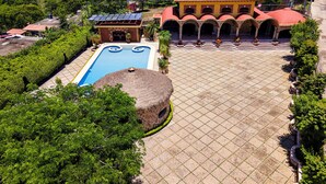 An aerial view of a resort with a swimming pool, a thatched-roof structure, and a large courtyard with tiled flooring. - Ideal fifth for rest! Swimming pool, foosball, barbecue and much more. (San Gabriel las Palmas)