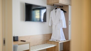 A modern bathroom with a wooden vanity, a mounted TV, and a robe hanging on a rack. - VRAHOS Executive Suite, Mani Suites (Agios Dimitrios)