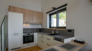 Une cuisine moderne avec des meubles en bois, un four encastré, un lave-vaisselle et une fenêtre qui laisse entrer la lumière naturelle.