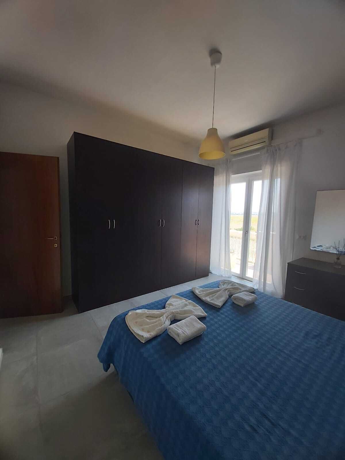 A bedroom with a large bed, dark wardrobe, and a window with curtains.