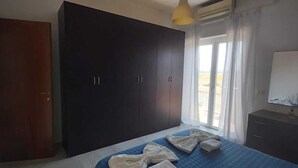 Une chambre avec un grand lit, une armoire sombre et une fenêtre avec des rideaux.