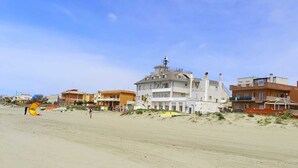 Un bâtiment situé sur la côte, doté d’une tour imposante, bordé d’une plage et entouré de logements.