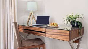 Un bureau moderne avec un ordinateur portable, une lampe, une assiette de nourriture et une plante en pot.