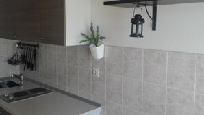 A modern kitchen with a built-in sink, a hanging plant, and a wall-mounted lantern. - Villa Mery (Rab)