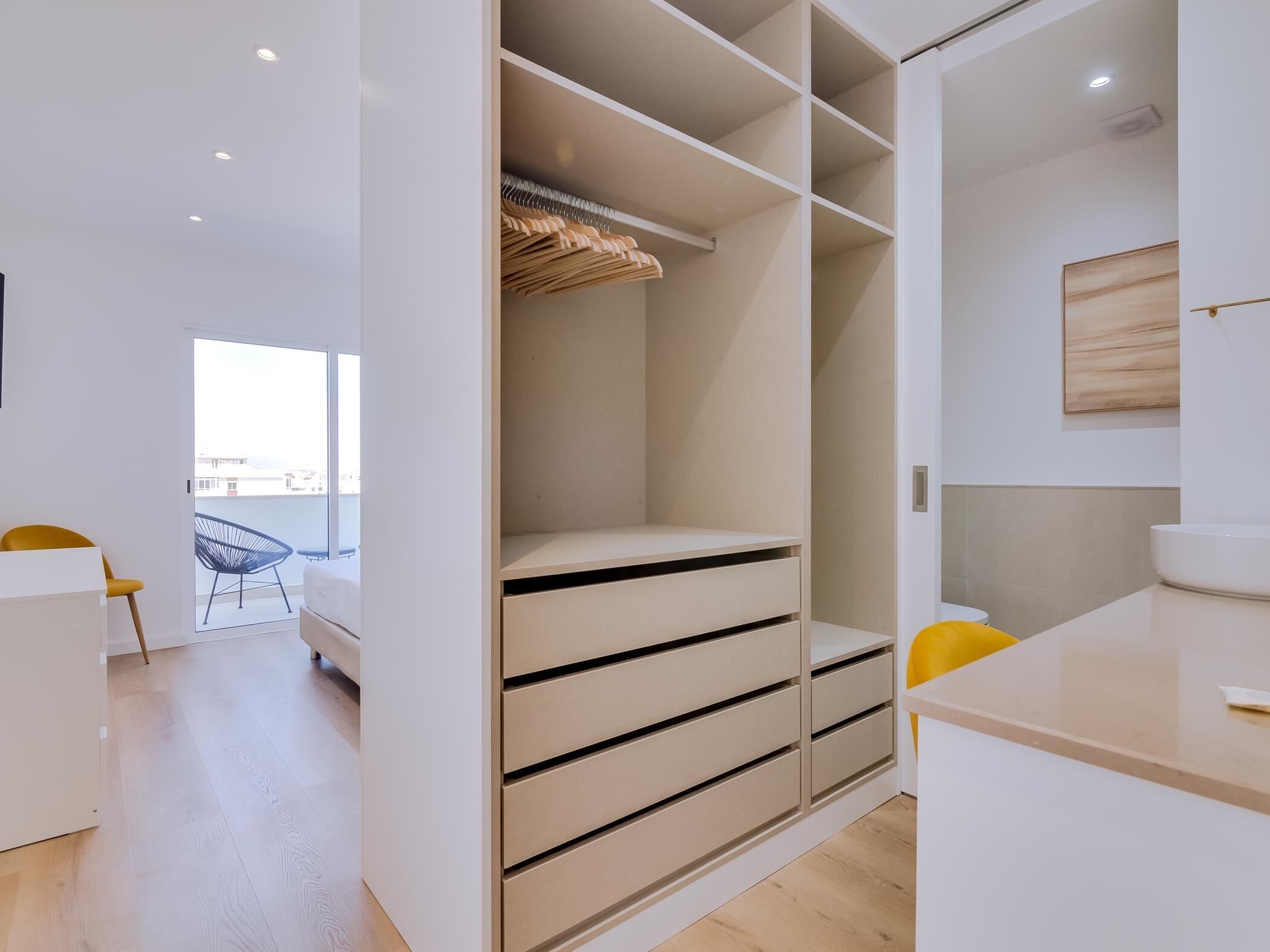 A modern room with a built-in wardrobe, a small table, and a chair.